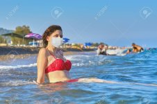 148516292-young-beautiful-caucasian-woman-in-red-swimsuit-with-desposable-facial-protective-su...jpg